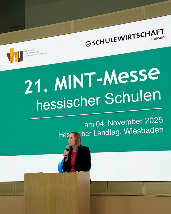 Begrüßung zur MINT-Messe Hessische Landtagspräsidentin Astrid Wallmann steht an einem Rednerpult mit Mikrofon vor einer großen Leinwand. Die Leinwand zeigt den Schriftzug „21. MINT-Messe hessischer Schulen“ sowie Datum und Ort: 4. November 2025, Hessischer Landtag, Wiesbaden.
