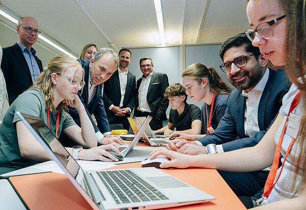 Gruppendiskussion und Schülerarbeiten an Laptops. Schüler arbeiten an Laptops.