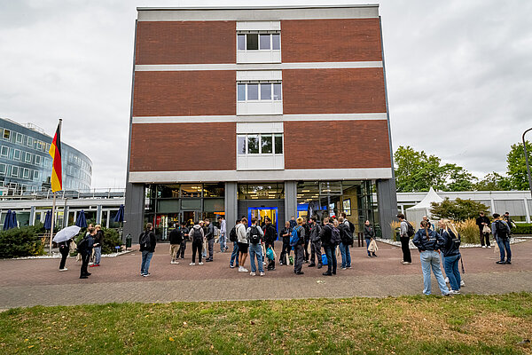 Menschen versammeln sich vor einem Gebäude.