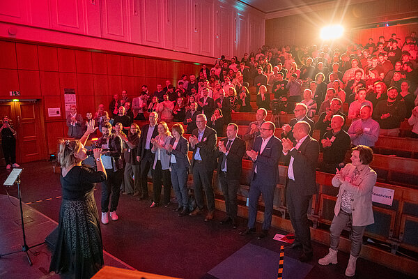Menschen applaudieren in einem Saal.