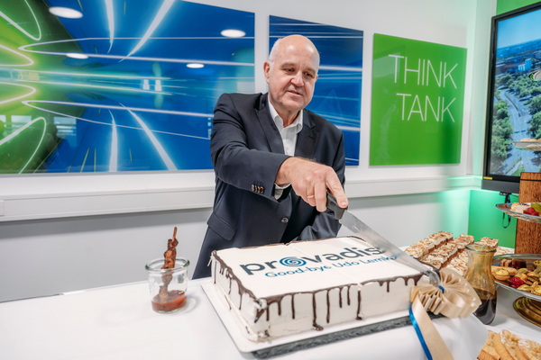 Dr. Udo Lemke schneidet eine rechteckige Torte mit Provadis-Logo und der Aufschrift „Goodbye Udo Lemke“ an, auf einem Tisch mit Dessertbuffet im Hintergrund.