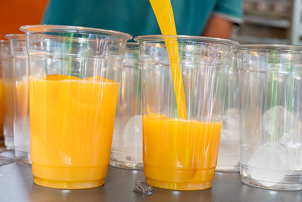 Orangensaft wird in Becher gegossen.